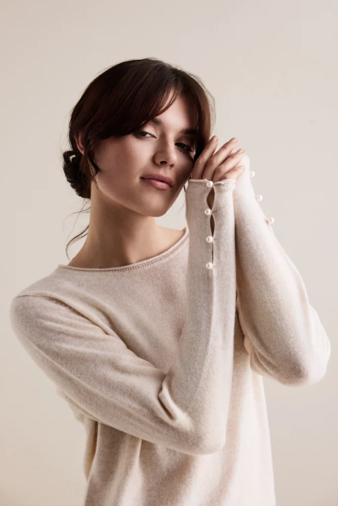 Woman in a beige, cashmere pullover with buttons on the sleeves